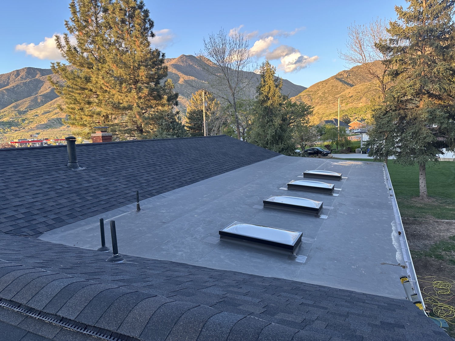 Flat TPO membrane roof with skylights and mountain views at sunset