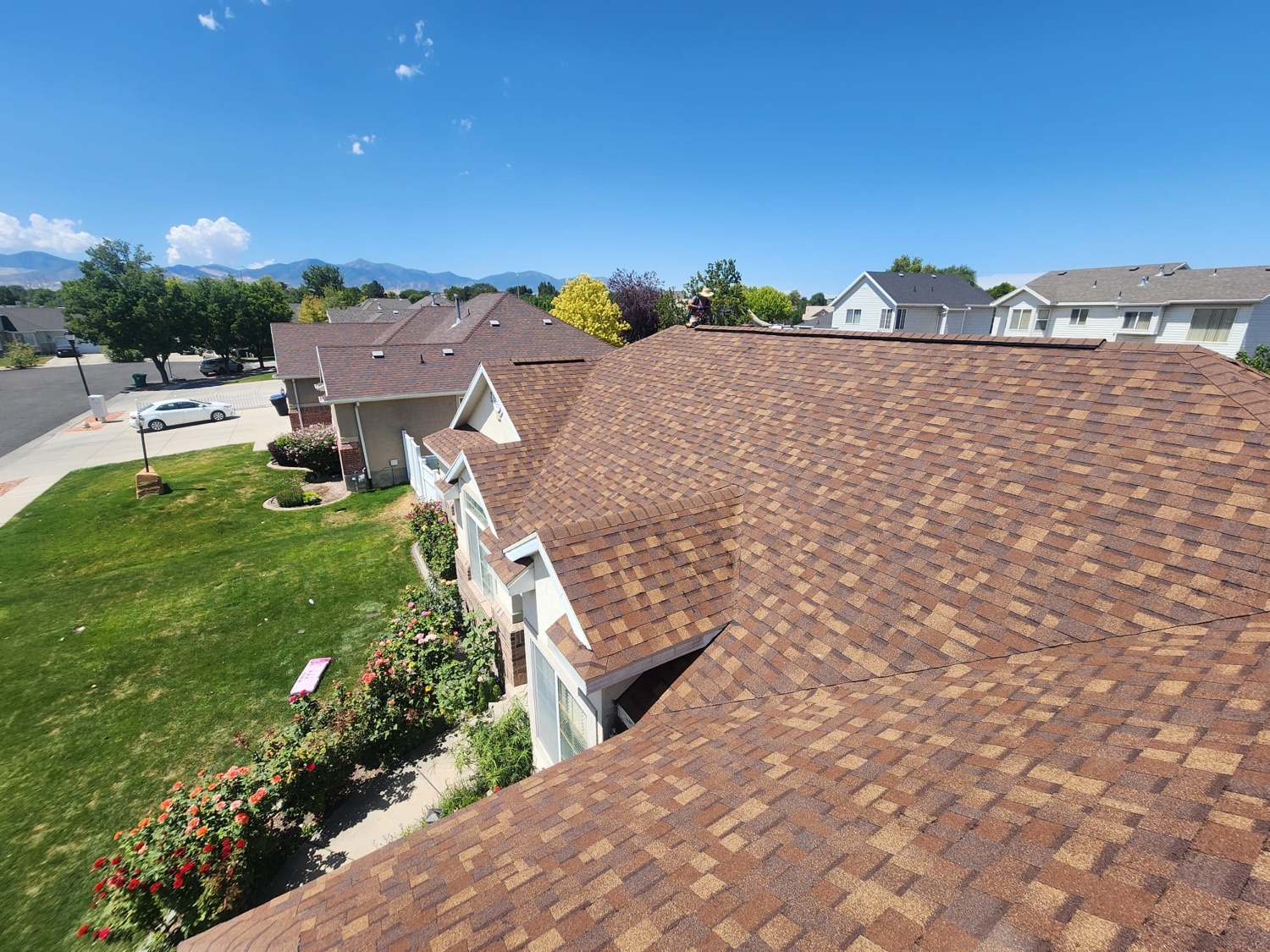 Completed asphalt shingle roof on a Salt Lake Valley home with the Wasatch mountains behind